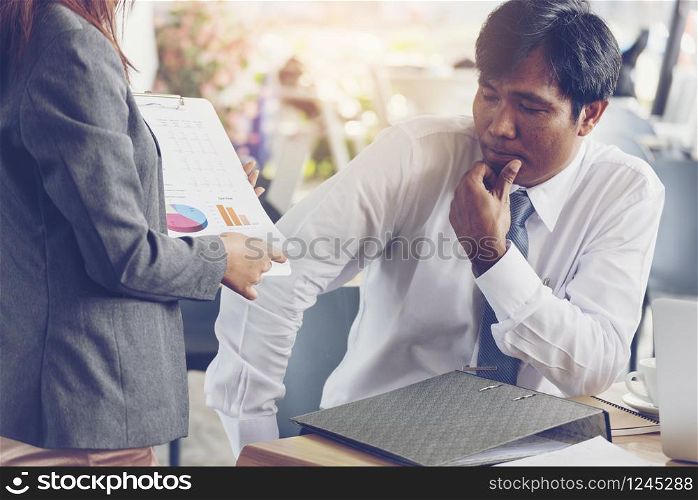 Asian Businessman thinking profit and loss about new project. Young secretary showing financial report.