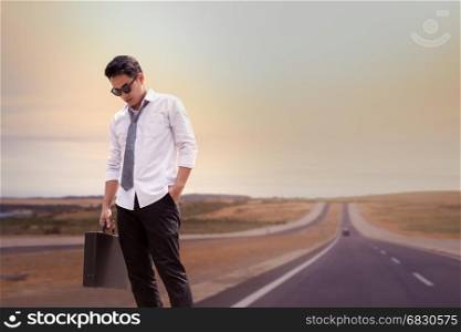 Asian Businessman tired and standing on road at upcountry out of modern city, travel concept