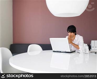 Asian businessman using white laptop in contemporary office space