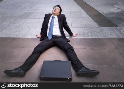 Asian businessman wearing glasses tired and briefcase for working, lay down on the floor