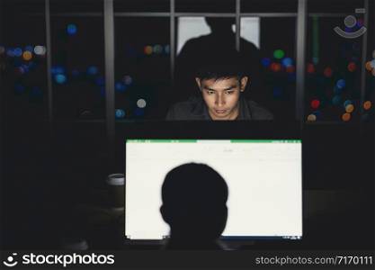 Asian businessman working hard late with her technology laptop in office, customer service and call center department,hard worker and overtime,team work with colleagues for success achievement concept