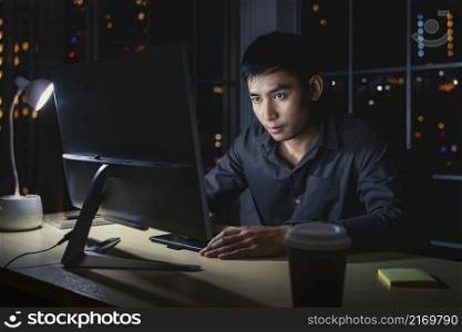 Asian businessman working hard late with technology computer in office, customer service and call center, team work with colleagues for success achievement project concept