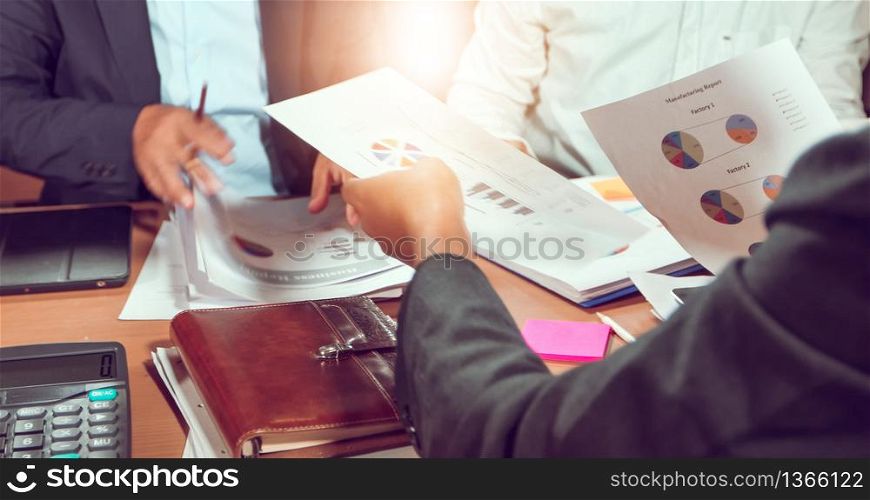 Asian businessmen and businesswomen analysis documents on office table with laptop computer and graph financial diagram working in the background