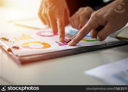 Asian businessmen and women working and point on graph financial diagram and analysis documents on office table