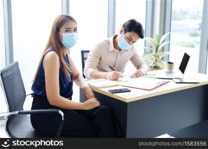 Asian businesspeople teamwork wearing mask for preventing covid19 virus and brainstorming in workplace at office. Healthcare and New normal lifestyle in business concept.
