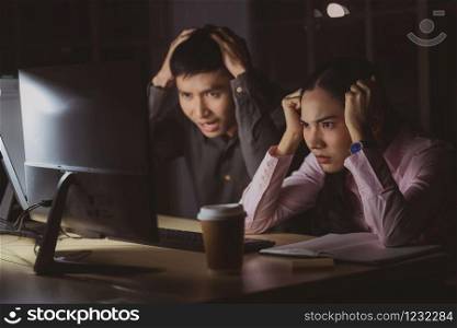 Asian businesswoman and businessman working hard late together with technology computer in office, Headache and problem resolution, team work with colleagues for success achievement project concept