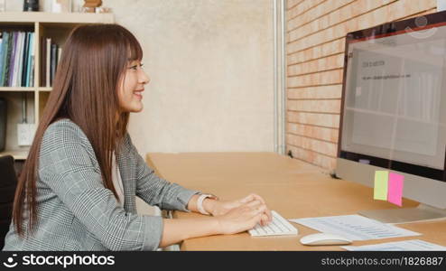 Asian businesswoman entrepreneur using computer desktop looking at screen working in internet from home office. Self-isolation, social distancing, quarantine for corona virus prevention.