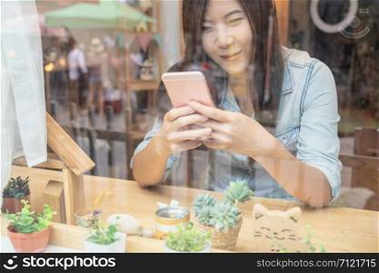 Asian businesswoman hand using the smart mobile phone with happiness action on the desk beside the glass in workplace or co-working space or modern office, business lifestyle concept