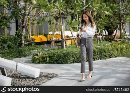 Asian businesswoman holding mobile phone texting message outside of office, Happy young woman using smartphone outdoor on urban city street, applications on cell phone, checking social media