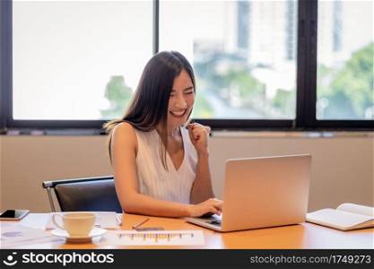 Asian businesswoman in casual suit are glad when completed doing online shopping via smart mobile phone application or technology laptop in modern office, business and lifestyle concept