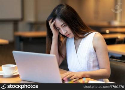Asian businesswoman in casual suit looking at annual report and thinking with serious action in modern office, business failure, healthcare and office syndrome concept