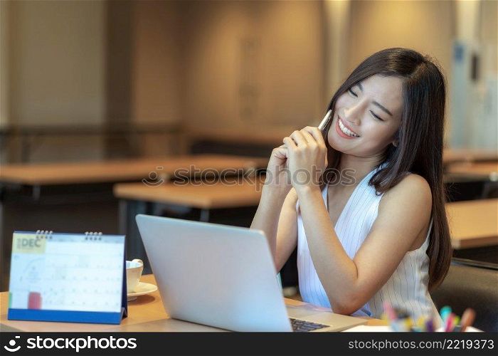 Asian businesswoman in casual suit looking at annual report with happiness action in modern office, business success concept