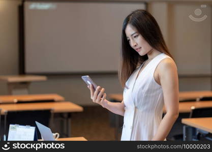 Asian Businesswoman in casual suit working with smart mobile phone and office supplies in modern office or meeting room, Business and worker concept