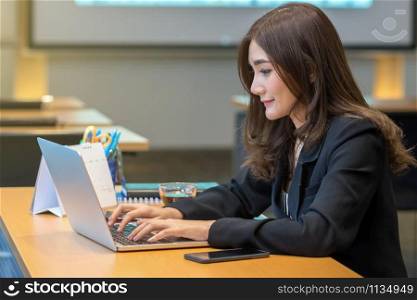 Asian Businesswoman in formal suit working with computer laptop and office supplies in modern office or meeting room, Business and worker concept