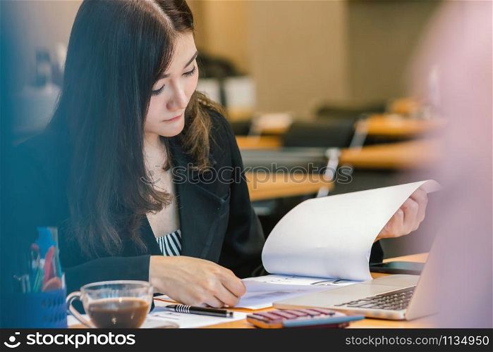 Asian Businesswoman in formal suit working with computer laptop and office supplies in serious action at modern office or meeting room, Business and worker concept