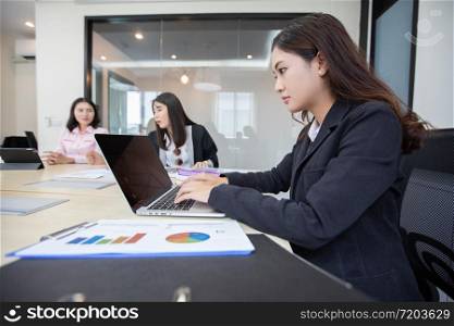 Asian businesswoman serious about the work and using notebook for business partners discussing documents and ideas at meeting