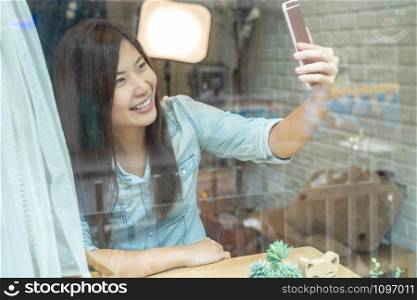 Asian businesswoman taking the selfie with happiness action in modern coffee shop or workplace or co-working space or modern office, lifestyle and leisure concept