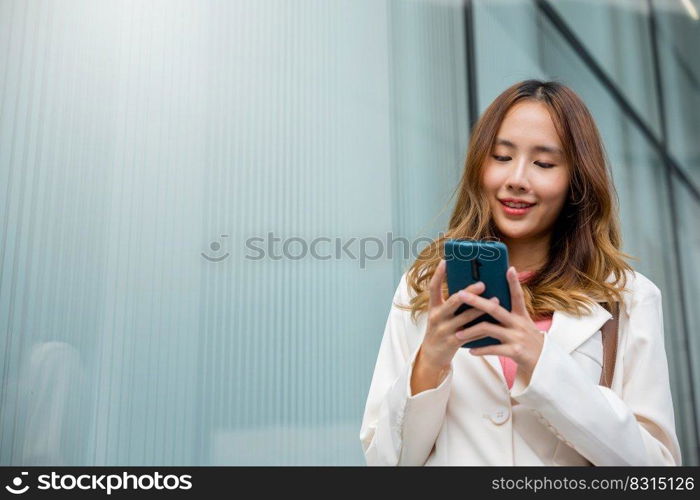 Asian businesswoman texting smartphone commuting work she walking near her office building in morning, Beautiful business woman smiling hold mobile phone outdoor walking on city street urban