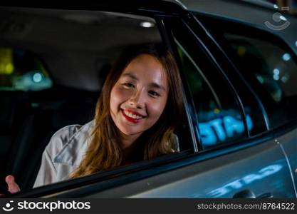 Asian businesswoman working late commuting from office in Taxi backseat with mobile phone in city at night after late work, Happy beautiful woman texting smartphone sitting car back seat in urban