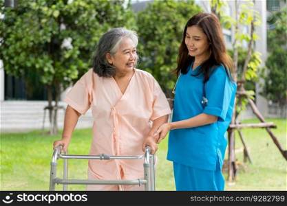 Asian careful caregiver or nurse hold patient hand and encourage patient, walking in garden. Concept of happy retirement with care from a caregiver and Savings and senior health insurance.