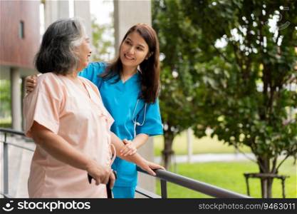 Asian careful caregiver or nurse hold patient hand and encourage patient, walking in garden. Concept of happy retirement with care from a caregiver and Savings and senior health insurance.