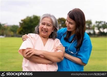 Asian careful caregiver or nurse hold the patient hand and encourage the patient in a garden. Concept of happy retirement with care from a caregiver and Savings and senior health insurance.