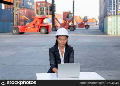 Asian cargo container worker of engineer woman use laptop in workplace area with concept of quality control for industrial business.