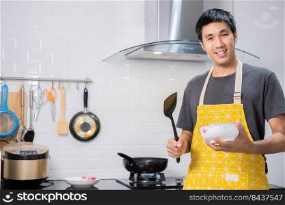 Asian chef fried eggs on pan to thai food in kitchen on gas stove The oil in pan boiling.Eggs and pork cooked. before serving to happy family to eat togetherness in home