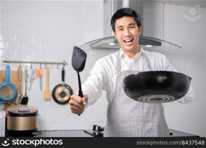 Asian chef fried eggs on pan to thai food in kitchen on gas stove The oil in pan boiling.Eggs and pork cooked. before serving to happy family to eat togetherness in home