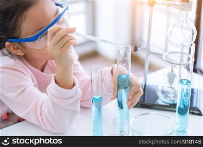 Asian child chemist holding flask and test tube in hands in lab learning chemistry experiment. Scientist chemistry and science education concept. Kids dream job occupation