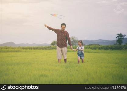 Asian child girl and father with a kite running and happy on meadow in summer in nature