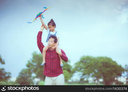 Asian child girl and father with a kite running and happy on meadow in summer in nature