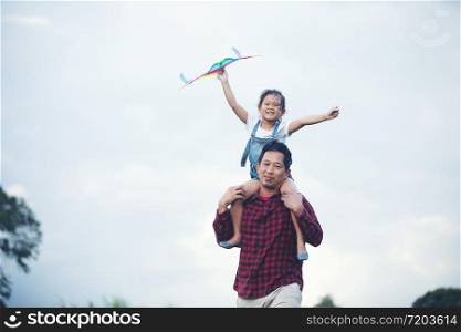 Asian child girl and father with a kite running and happy on meadow in summer in nature