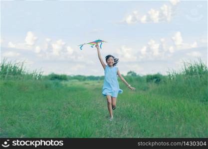 Asian child girl with a kite running and happy on meadow in summer in nature