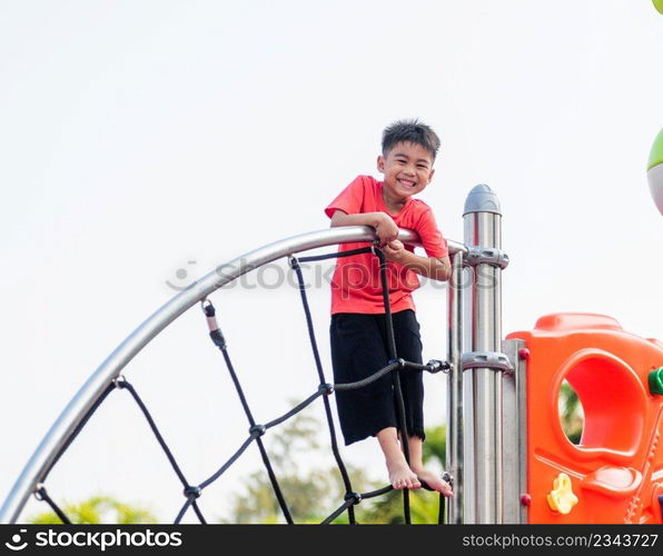 Asian child smiling playing climbing outdoor playground, happy preschool little kid having funny while playing climbs on a rope climbing net on playground equipment in daytime in summer, Little boy