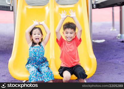 Asian child smiling playing on slider bar toy outdoor playground, happy preschool little kid having funny while playing on the playground equipment in the daytime in summer, Little girl   boy climbing