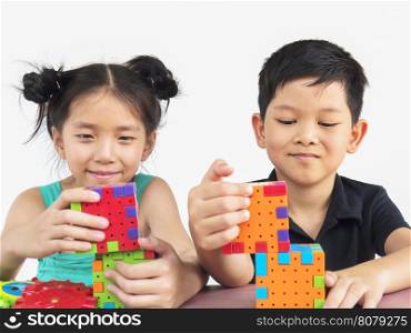 Asian children are playing puzzle plastic block creative game to practice their physical and mental skill
