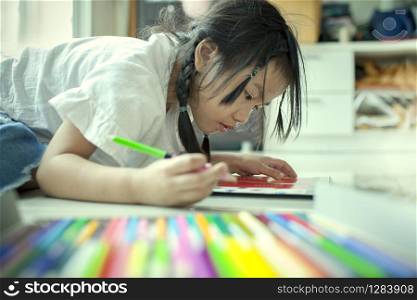 asian children playing and painting color pencil on paper book in home school