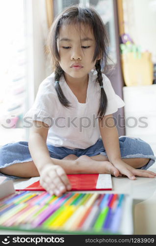asian children playing color pencil in hoime living room