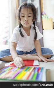 asian children playing color pencil in hoime living room