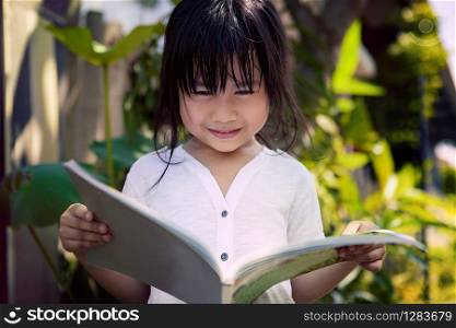 asian children reading a book in home garden