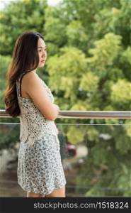 Asian Chinese business woman relax at balcony and look at green foliage leaf to relax after hard working. CEO girl get fresh air and greenery atmophere to relief stress or depression from work.