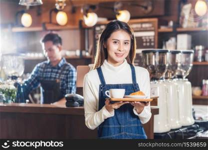 Asian Coffee shop owner serving bakery cake and coffee cup to customer in coffee shop, Small business owner and startup in coffee shop and restauran, waitress and barista concept
