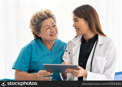 Asian confidence doctor using digital tablet expressing health concerns with old elderly woman patient sit on wheelchair