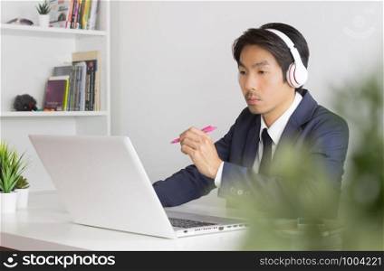 Asian Consultant or Asian Businessman in Formal Navy Blue Suit Talking and Suggest Customer on Laptop Screen in Office. Consulting services from professional consultant
