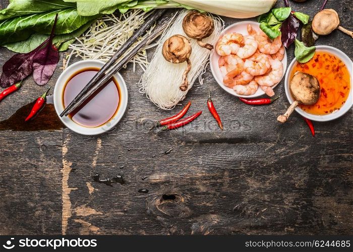 Asian cooking ingredients with soy and sweet-sour sauce and chopsticks on rustic background, top view. Asian food concept.