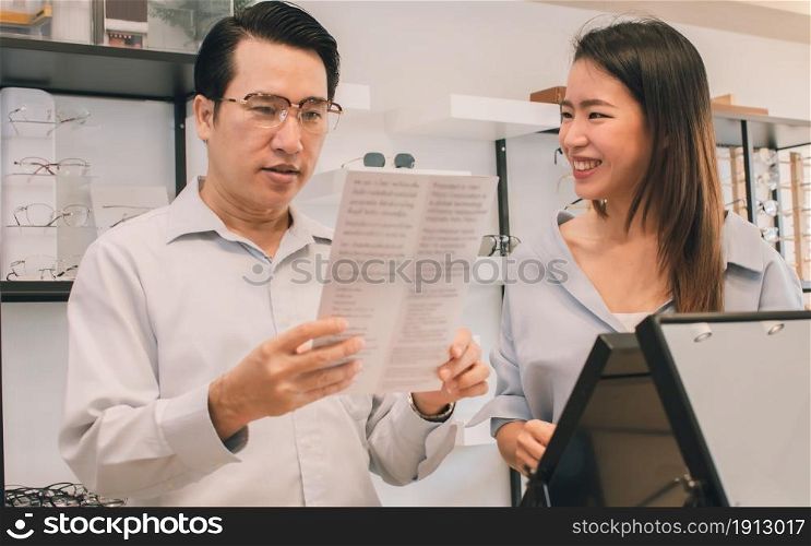 Asian couple choosing, shopping and purchasing eyeglasses in the store together. Discount, Sales and Optical Concept.