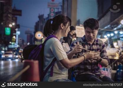 Asian couple eating in Street food Night market for tourist on chinatown at yaowarat road in bangkok