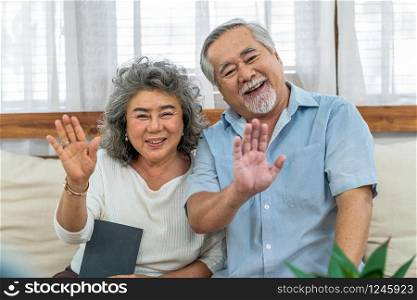Asian couple Grandparent greeting and talking with Granddaughter with happy feeling via video phone call by mobile phone in house, Long live and Elderly society, Warm family and happiness concept