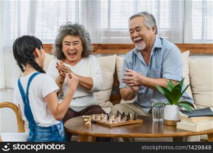 Asian couple Grandparent with grandchild playing the chess with happy feeling together, celebrating and winning, Long live and Elderly society,Warm family and happiness,social distancing concept